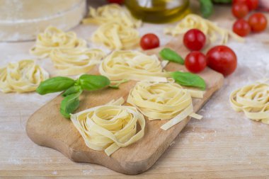 taze ev yapımı makarna makine makarna, fesleğen. bir tahta üzerinde domates