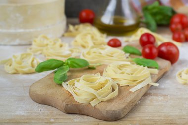 taze ev yapımı makarna makine makarna, fesleğen. bir tahta üzerinde domates