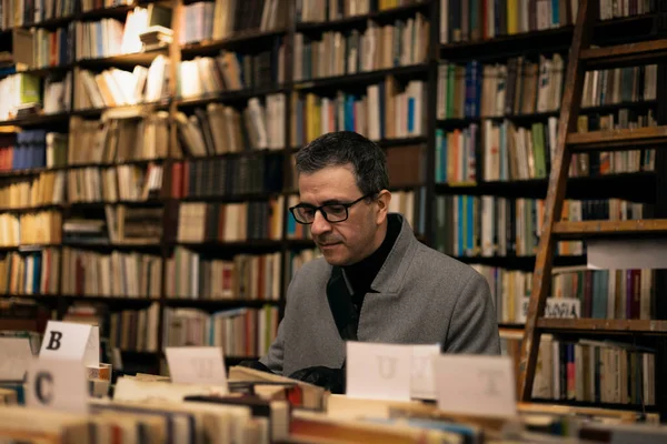 Elegant middle-aged man looking for a book in a classic bookstore Conceptual of reading, lifestyle, elegance in middle age