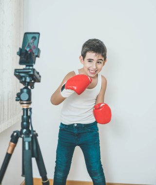 Çocuk cep telefonuyla kayıt yaparken boks yapıyor. Yaşam tarzı, spor, evde öğrenme kavramı.