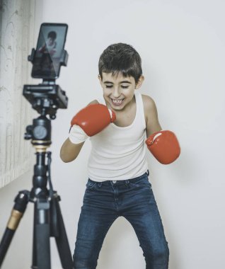 Çocuk cep telefonuyla kayıt yaparken boks yapıyor. Yaşam tarzı, spor, evde öğrenme kavramı.