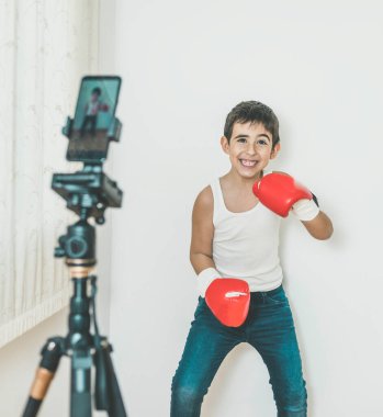 Çocuk cep telefonuyla kayıt yaparken boks yapıyor. Yaşam tarzı, spor, evde öğrenme kavramı, yeni normal.