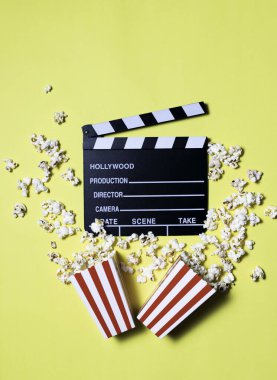 Sinema, eğlence, görsel ve işitsel konulardaki kavramsal sarı arka planda film ve patlamış mısır.