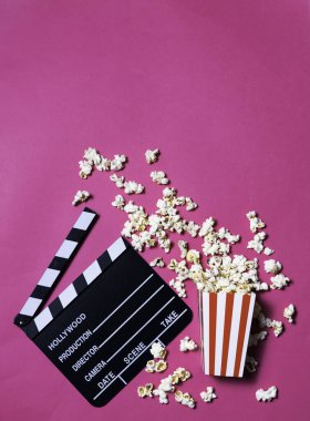 Sinemanın, eğlencenin, görsel ve işitsel kavramının fuşya pembe arka planı üzerinde film alkışları ve patlamış mısır.