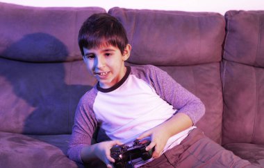 Çocuk, kırmızı ve mavi ışıkların altında video oyunları oynuyor. Teknoloji kavramı, siber punk estetiği.