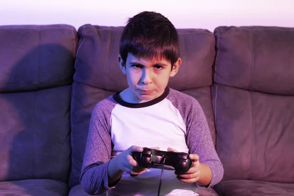 Boy plays video games from the couch under red and blue lights Conceptual of technology, cyberpunk aesthetic