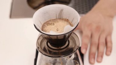 Sütlü kremayla karıştırılmış sıcak kahve. Kokulu kahve çekirdekleri kızartma tavasında kızartılır, duman kahve çekirdeklerinden gelir. Kahve tohumlarını kapat. Kokulu kahve çekirdekleri kavrulmuş. Kahve espresso yakın çekim buhar içeceği sıcak.