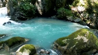Yavaşça büyük ahşap bir iskelenin üzerinden göle doğru yürüyorlar ve göl suyunun üzerinde uçuyorlar. Bir dağ ormanı gölünde çam ağaçlarıyla birlikte turkuaz su. Mavi göl ve yeşil orman gölü havadan görünüyor.. 