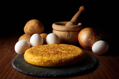 Lezzetli bir İspanyol omletinin yakın çekimi ve arka plandaki malzemeler, İspanya 'dan geleneksel bir yemek.