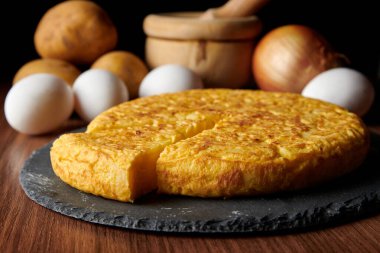 Lezzetli bir İspanyol omletinin yakın çekimi ve arka plandaki malzemeler, İspanya 'dan geleneksel bir yemek.