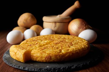 Lezzetli bir İspanyol omletinin yakın çekimi ve arka plandaki malzemeler, İspanya 'dan geleneksel bir yemek.