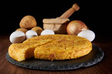 Lezzetli bir İspanyol omletinin yakın çekimi ve arka plandaki malzemeler, İspanya 'dan geleneksel bir yemek.
