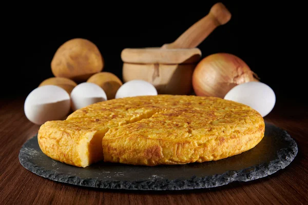 Lezzetli bir İspanyol omletinin yakın çekimi ve arka plandaki malzemeler, İspanya 'dan geleneksel bir yemek.