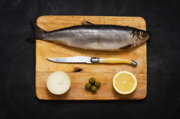 Limon ve soğan bir kesme tahtası üzerinde ringa balığı