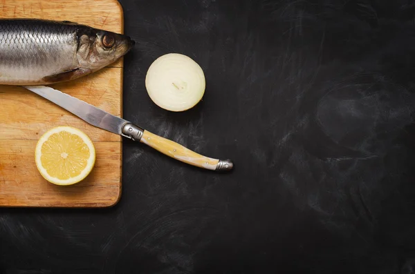 Limon ve soğan bir kesme tahtası üzerinde ringa balığı