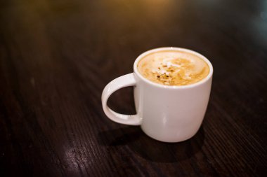 Ahşap masada arka lambalı kahve fincanı.