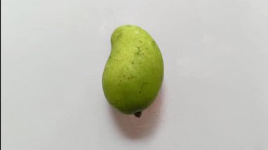 Beyaz arka planda izole edilmiş yeşil bir mangoya yakın plan. Tropikal meyve kavramı, tazelik, organik gıda, doğal üretim, sağlıklı beslenme, minimum bileşim, aşçılık malzemesi ve taze egzotik meyve..