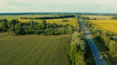 Hava aracı gün batımında arazi aracı ile otobanın üzerinde uçuyor. Otomobilli bir banliyö yolunun havadan görünüşü. Arabalı bir yol manzarası. Otobanda bir aracın hava görüntüsü. 