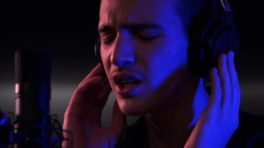 Şarkıcı bestesini bir müzik stüdyosunda kaydediyor. Genç Çocuk mikrofona bir şarkı söylüyor. Profesyonel bir müzisyenin, kulaklıklı bir şekilde şarkı söylerken çekilmiş sinematik görüntüleri.