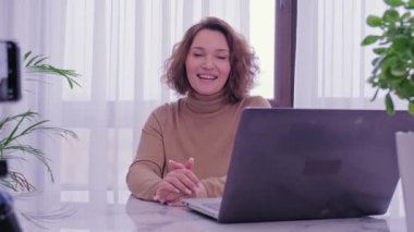 Kadın blogcu video bloğunu evde kaydediyor. Gülümseyen kadın video blogunu kaydediyor. Yetişkin bir kadın blog kanalı için kameranın önünde konuşuyor. Vlog kaydedicisi akıllı telefon kullanarak çevrimiçi yayın yapıyor