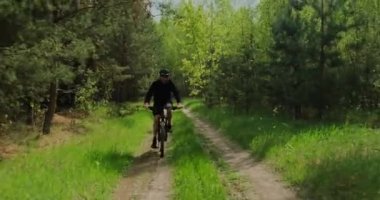 Orman yolunda bisiklet sürerler. Ormanda bisiklete binen bir adam. Bisiklet kasklı yetişkin bir adam yazın MTB bisikletine biner..