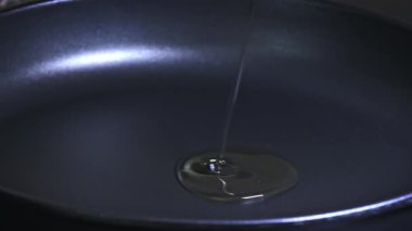 Aşçı kızartma tavasına ayçiçeği yağı döker, makro shot. Kızartma tavasına yemek yapmak için yavaş yağ akışı. Zeytin yağı kızartma tavasına dökülür..