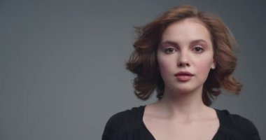 Orta boylu, kıvırcık kahverengi saçlı güzel bir kadın. Çekici kahverengi saçlı bir kadının yakından çekilmiş yüzü. Seksi görünüşlü seksi bir manken. Ağır çekim. Moda modeli stüdyodaki kameraya bakıyor.. 