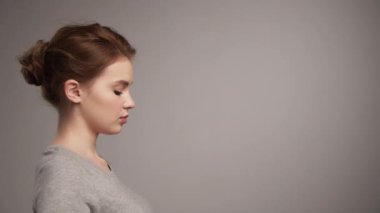Koruyucu tıbbi maske takan genç bir kadının portresi, stüdyo geçmişi, yavaş çekim. Sosyal uzaklık ve yeni normallik. Kadın tıbbi maske takıyor, virüs önleme.