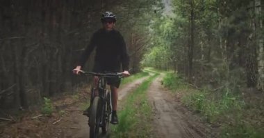 Orman yolunda bisiklet süren genç bir adam. Dağ bisikleti süren bir genç ormanda geziyor. Bisiklet kasklı bir adam MTB bisikleti sürüyor..
