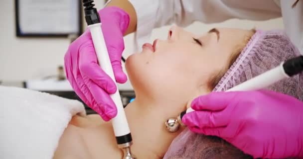 顔のケアのための化粧品の手順にスパサロンの女性 美容師は女性を顔に治療手順を作る 美容師は プロの機器を使用して医療手順を行います — ストック動画