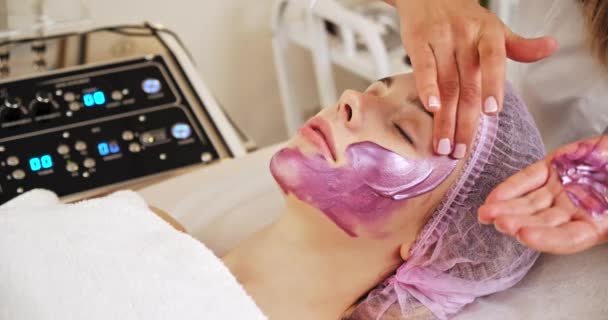 Cosmetólogo Aplica Una Mujer Una Máscara Terapéutica Cara Mujer Salón — Vídeos de Stock
