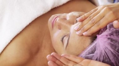 Yüz bakımı için kozmetik işlemleri yapan bir kaplıcadaki kadın. Kozmetik uzmanı kadın yüzüne kozmetik krem sürüyor. Güzellik tedavisi. 