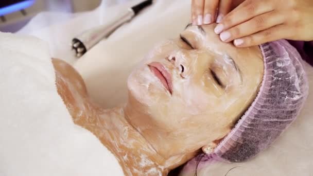 美容师在女人脸上做治疗性按摩 在温泉沙龙里做美容护理的妇女 美容师用润肤霜按摩脸部 — 图库视频影像
