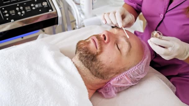학자는 남성의 얼굴에 의학적 처방을 내립니다 관리를 화장품 시술을 미용실에 — 비디오
