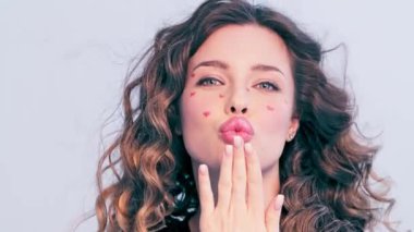 Yavaş hareket, güzel bir kız öpücük yolluyor. Model stüdyodaki kameraya bakar ve hava öpücüğü gönderir. Öpücük jestli seksi kız..