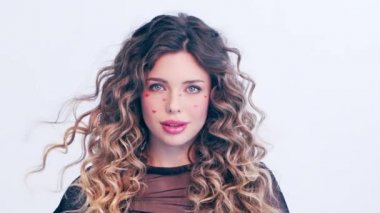 Yüzünde kırmızı kalpler olan güzel bir kız. Rüzgarda savrulan uzun saçlı güzel bir genç kadın. Model stüdyodaki kameraya bakar. Çekici bir sarışının yakın plan yüzü. Yavaş çekim