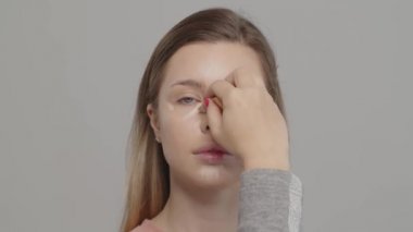 Makyaj sanatçısı ya da stilist, kadın modelin yüzüne ıslak sünger kullanarak temel oluşturur. Yüze kozmetik kapatıcı taban uygulaması. Profesyonel makyaj. Makyaj hocası sınıfı.  