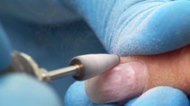 Manikürcü jöle cilası ya da manikür makinesi kullanarak tırnaklarından akrilik çıkarma sürecinde. Kuafördeki donanım manikürü. Güzellik salonunda çivi manikür işlemi. Manikür Salonu.