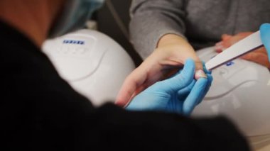 Evde çivi bakımı. Manikürcüde tırnak tedavisi. Tırnak bakım sürecinin ana omuzunun arkasından bir manzara.. 