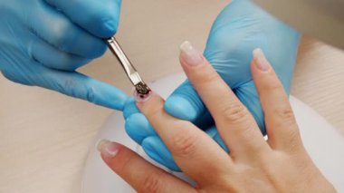 Manikürcü jöleyle oje sürüyor. Tırnaklarına akrilik oje sürme. Çivili Shellac uygulaması. Manikür servisi. Uzman, müşterinin tırnağını berrak jelle kaplıyor. Kapat.. 