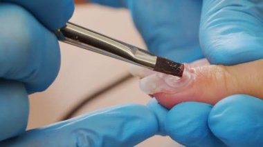Manikürcü jöleyle oje sürüyor. Tırnaklarına akrilik oje sürme. Çivili Shellac uygulaması. Manikür servisi. Uzman, müşterinin tırnağını berrak jelle kaplıyor. Kapat.. 