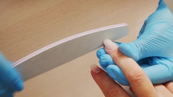 マニキュリストは 特別なネイルファイルで爪の形状をファイルし ビューを閉じます マニキュア師は爪のファイルで爪を形成します 美容室でのネイルケアのプロセス ネイルファイル処理 — ストック動画