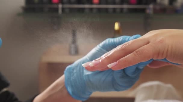マニキュリストは古いアクリル釘を扱う前に爪に防腐剤をスプレーします マニキュアの前に消毒剤で爪の治療 女性の手に消毒剤を適用する — ストック動画