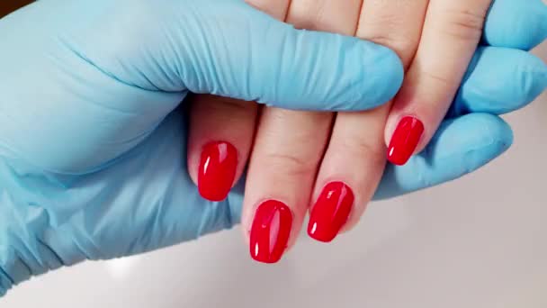 赤い色のファッショナブルなマニキュアと女性の手の4K動画 爪のマスターは赤いマニキュア爪を示しています 閉じます 爪の美しさ 古典的な赤いマニキュア マニキュリストは自分の作品を見せる — ストック動画