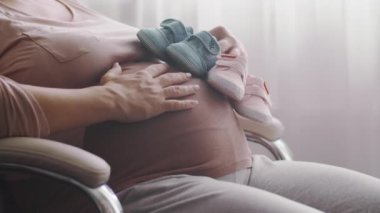 Mutlu hamile kadın ikiz bekliyor. Hamile bir kadın çocuğuna bakarken kendini mutlu hissediyor. Evde tek başına dinlenen hamile bir kadın koca karnına dokunuyor. Yavaş çekim 