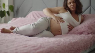 Müstakbel anne hamilelik acısı çekiyor. Hamile bir kadın kötü bir şekilde yatarken acı çekiyor. Hamile yetişkin bir kadın doğum beklerken acı hisseder. Hamile bir kadın karın ağrısından uyuyamaz.