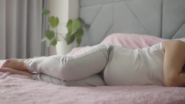 妊娠中の女性は赤ん坊が寝室で休んでいるのを期待している 妊娠中の成人女性は一人で家で寝ている 女性の妊娠と産前ケア スローモーション4Kビデオ — ストック動画