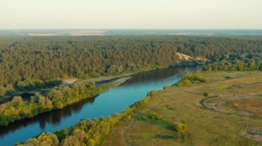 Gün batımında nehri olan güzel bir manzaranın üzerindeki hava manzarası. İnsansız hava aracından gelen hava manzarası güzel bir yaz manzarasının üzerinde uçar.. 