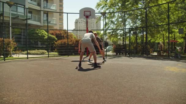 人们在一个温暖的夏日里打篮球 在阳光明媚的夏日 两名青少年在室外场地打一场篮球赛 攻击和防御 无射击 — 图库视频影像