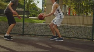 Sıcak bir yaz gününde sokak basketbolu oynayan insanların videosu. Güneşli bir yaz gününde açık hava sahasında basketbol oynayan iki gencin görüntüleri. Hücum ve savunma, sayı, sayı.